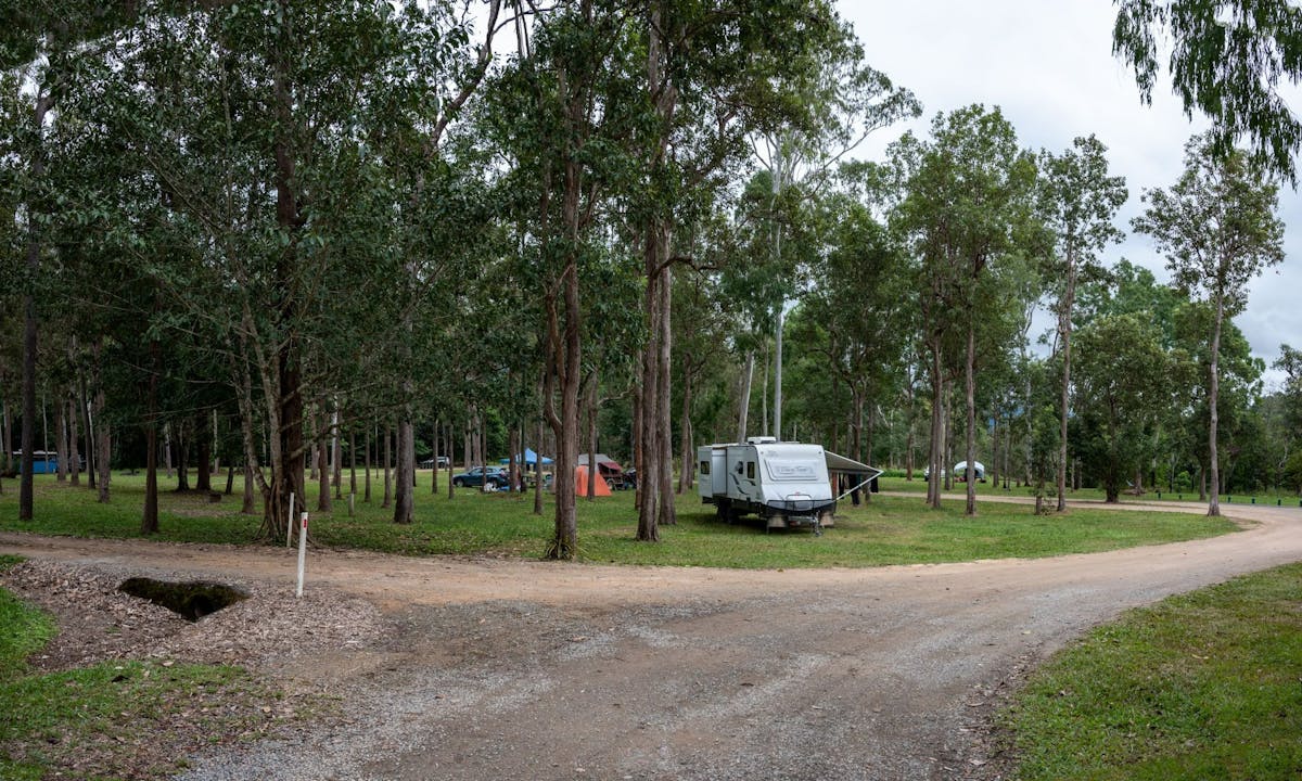 Open camping area with a caravan and tents.