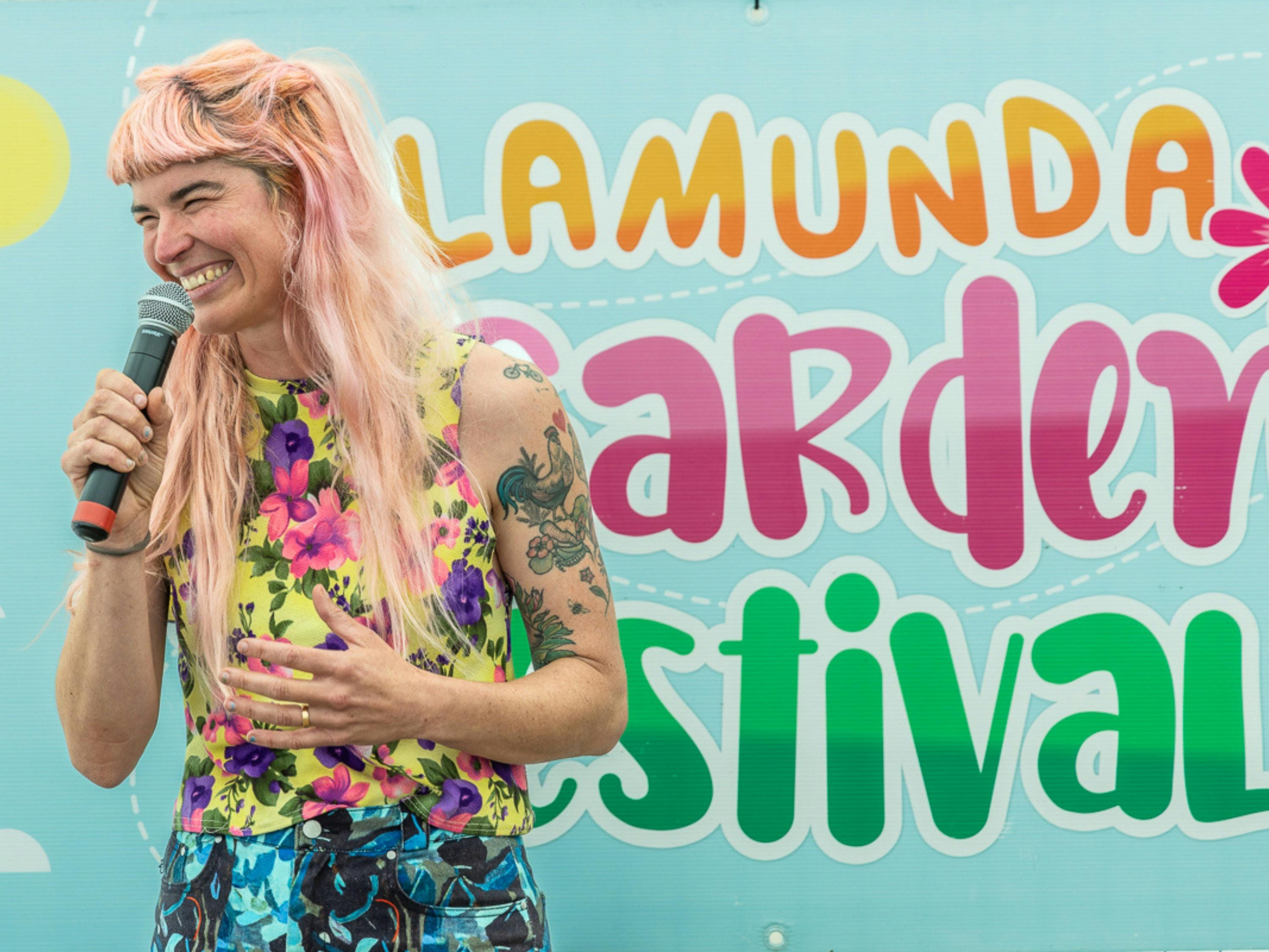 Hannah Moloney laughs on stage in front of the festival sign.