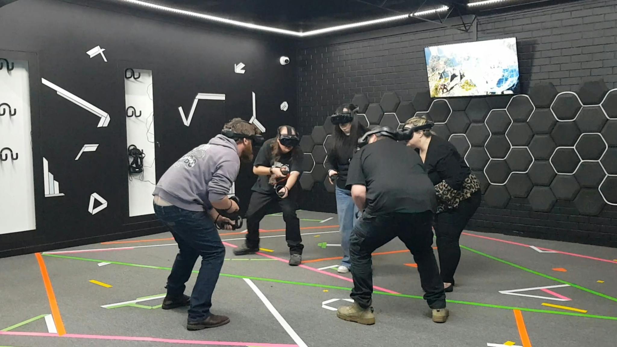 Five people wearing VR headsets crouching and holding virtual objects