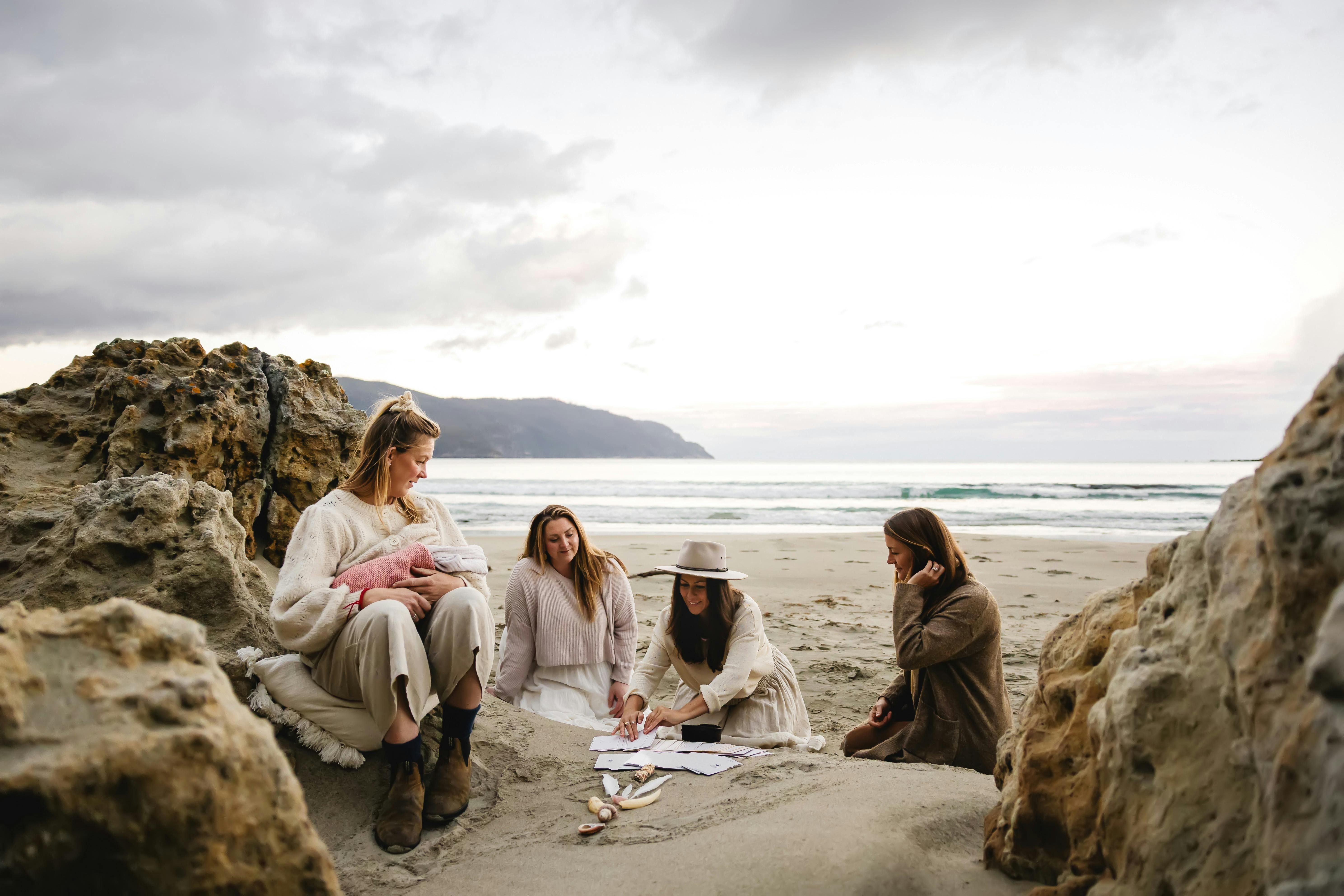 4 women in a womens circle on the beach