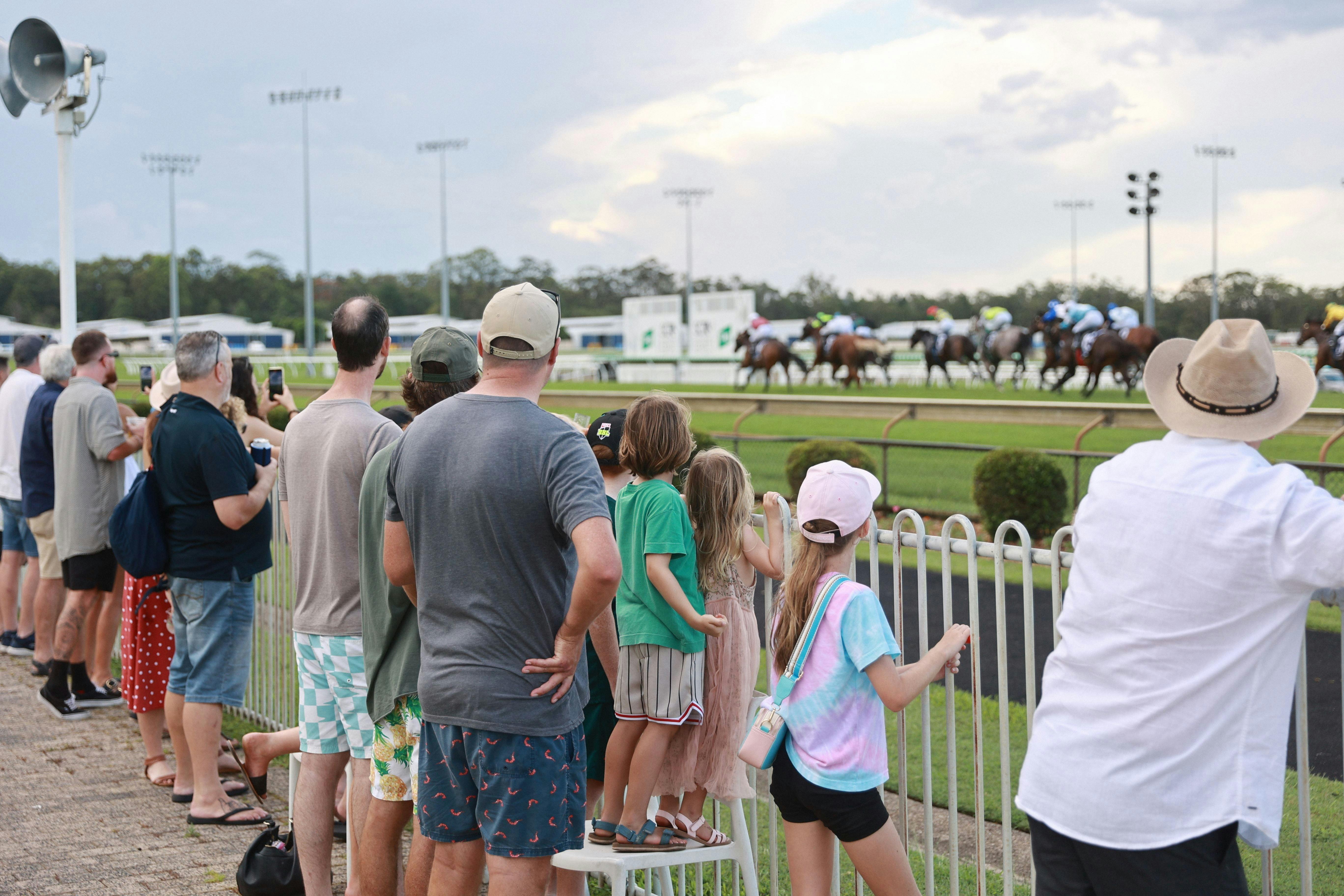 Families along the fence line watching the horse race in the background