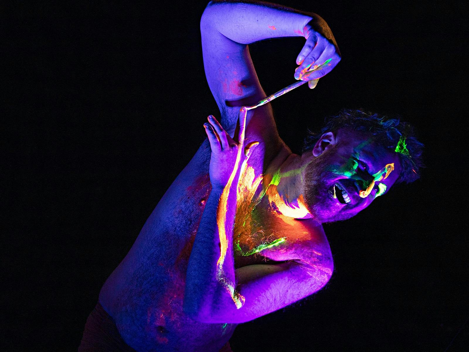 Man painting his arm with UV body paint