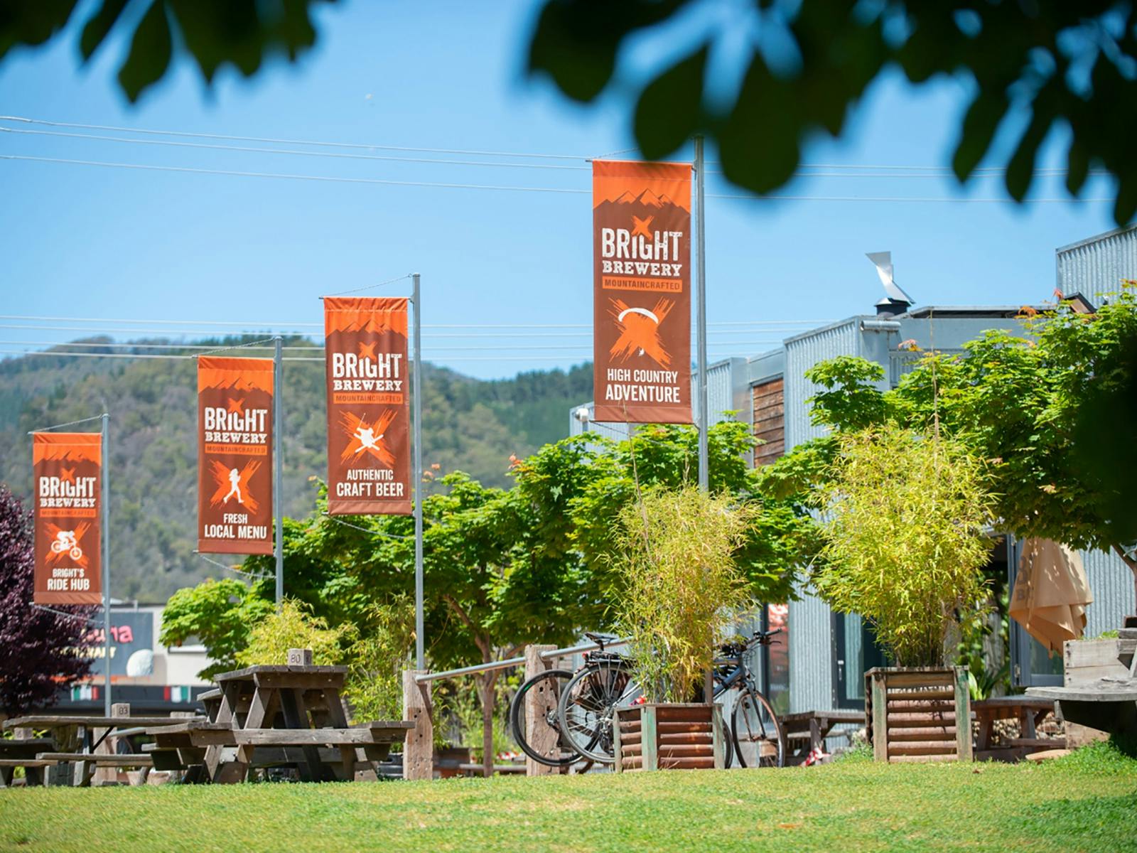 Brown and orange Bright Brewery flags outside a building with green grass and blue sky