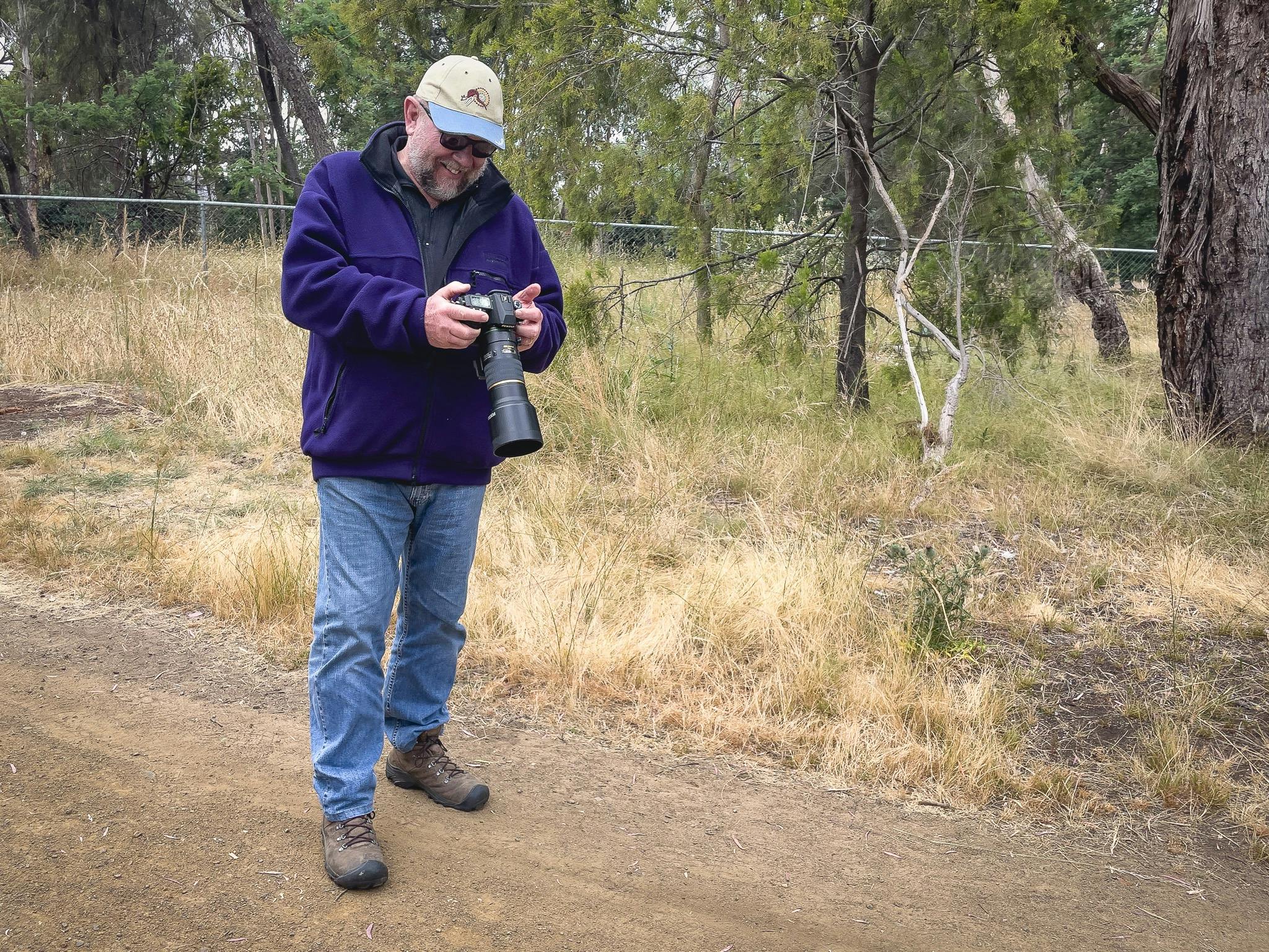 A male photographer with a big smile on his face as he reviews the photo just taken - successfully