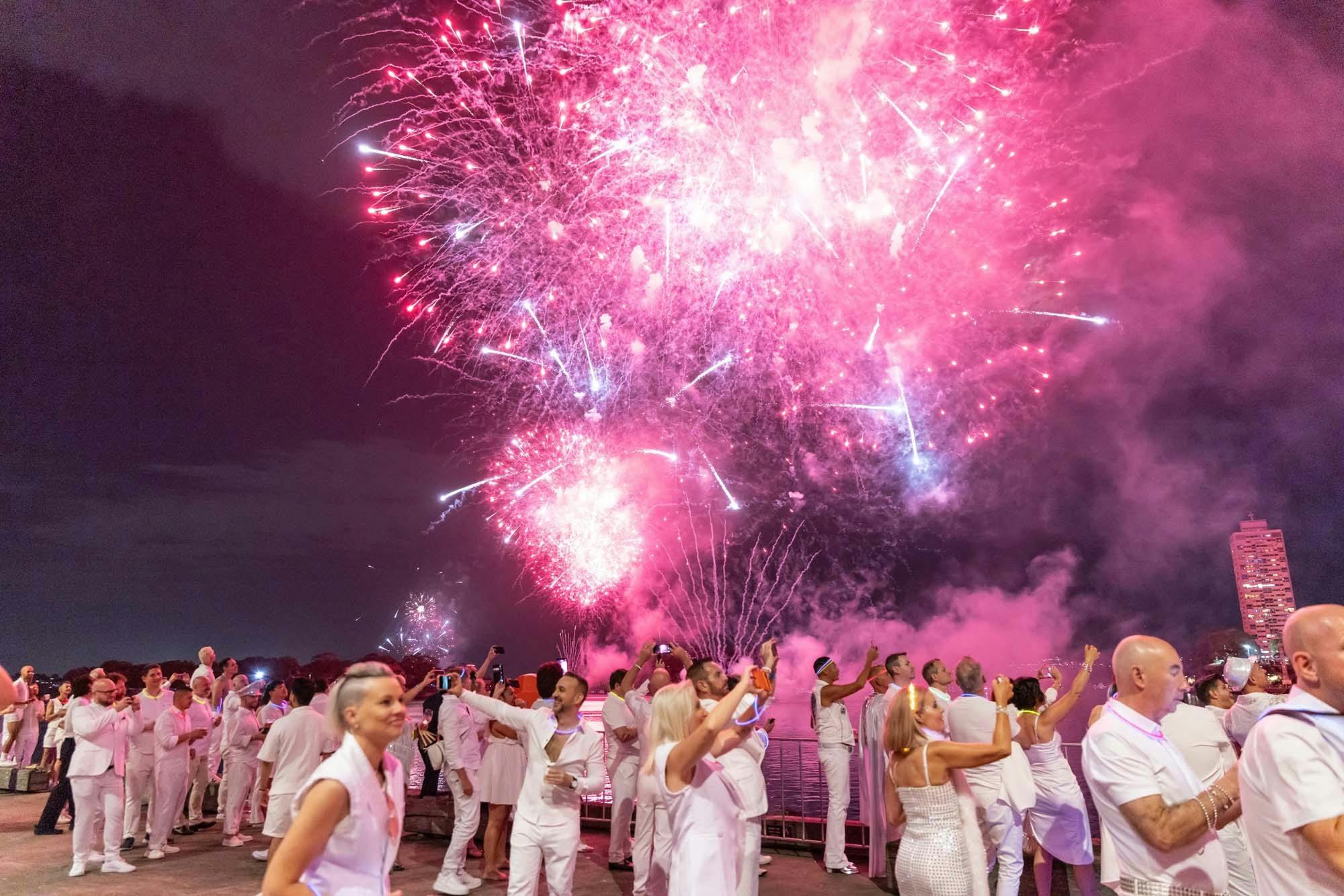 Guests in white watching fireworks beside Sydney Harbour.
