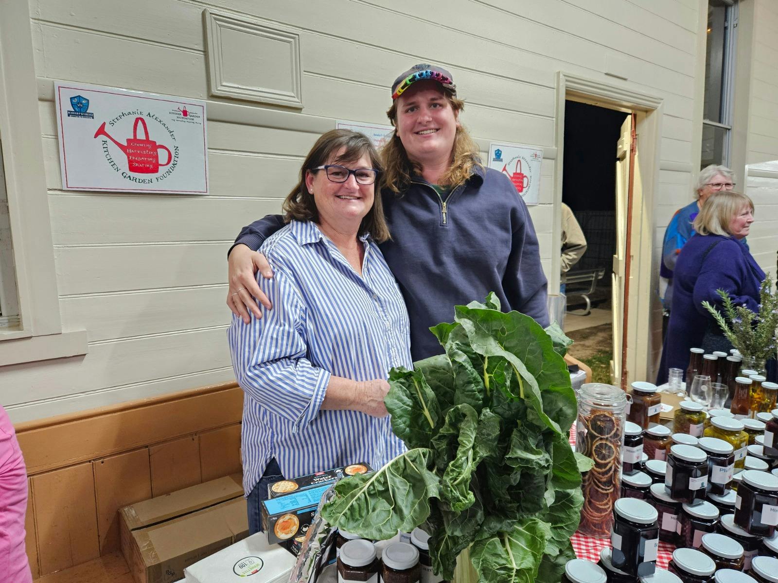 two people in front of table of preserves