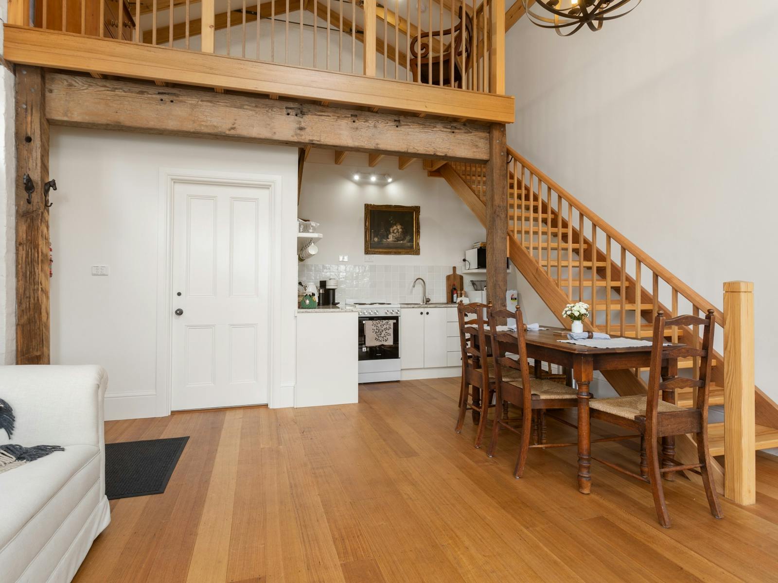 wooden floors in downstairs lounge dining area showing wooden stairs leading to loft bedroom