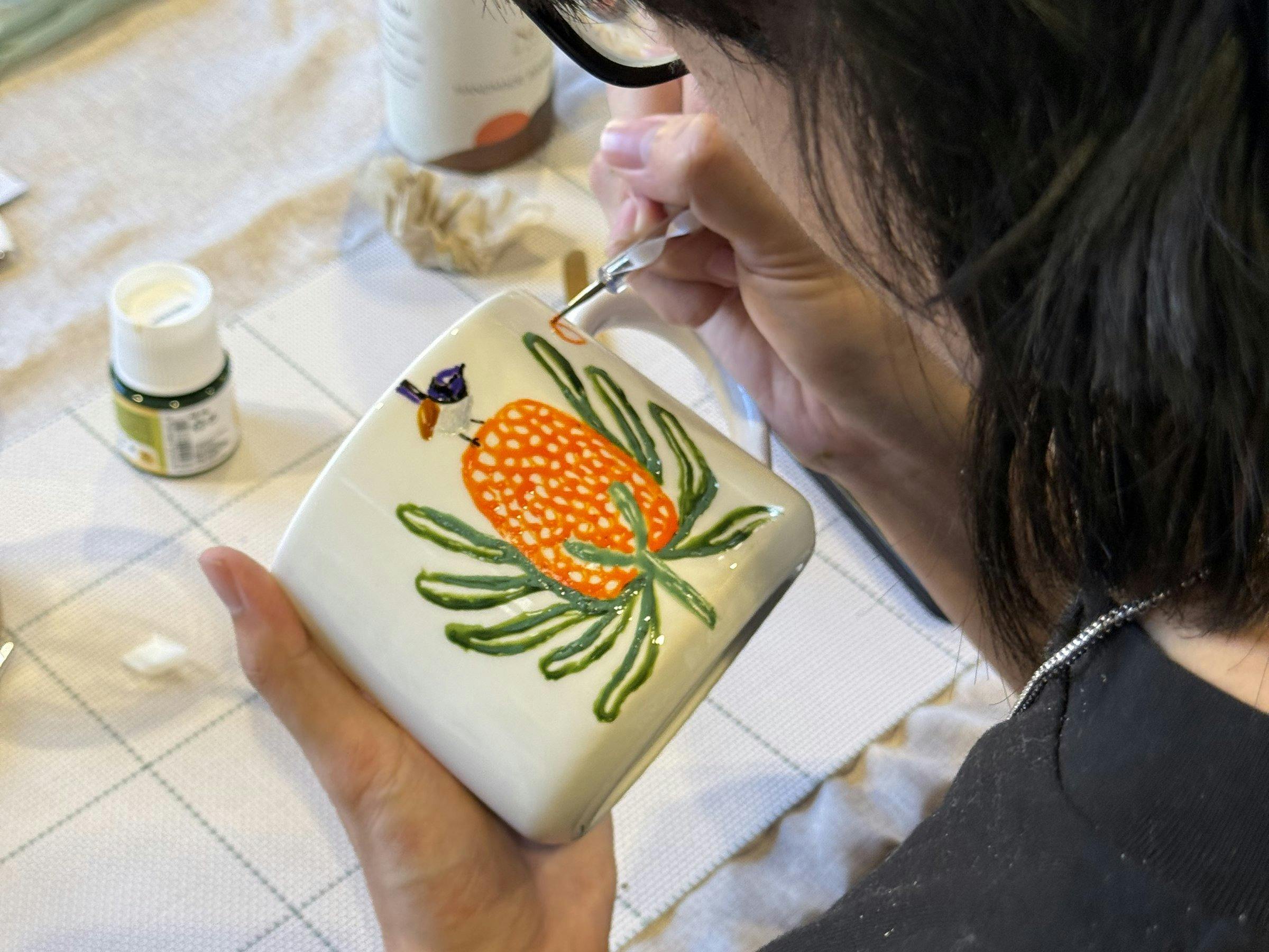 Guest hand-painting a ceramic cup at a NOA Matcha workshop