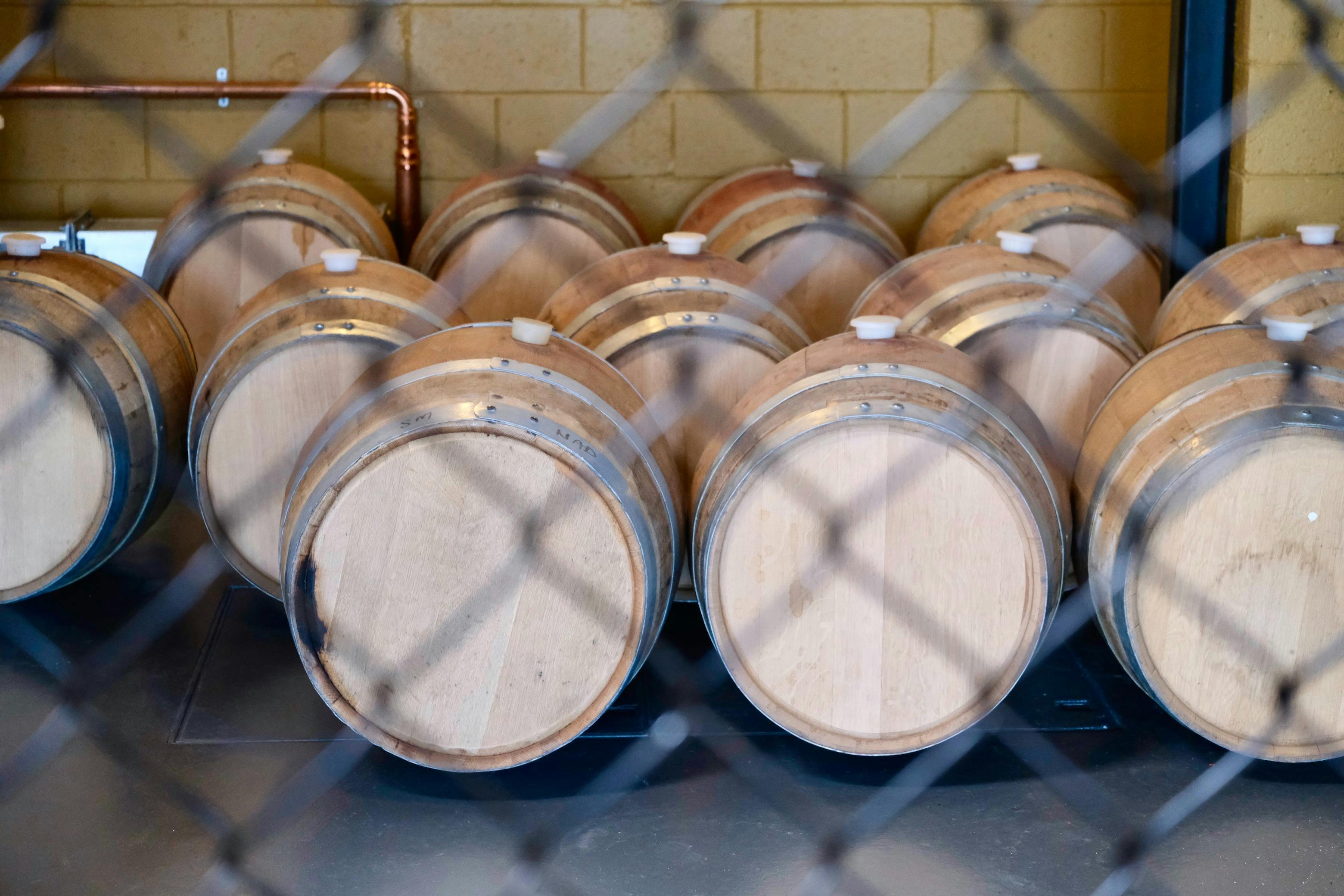 In the still room whisky casks lined up behind wire mesh fence