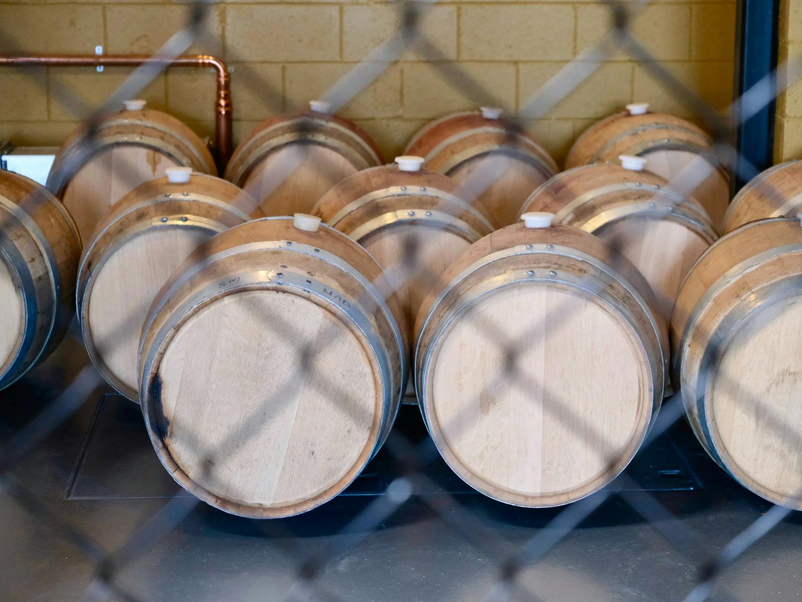 In the still room whisky casks lined up behind wire mesh fence