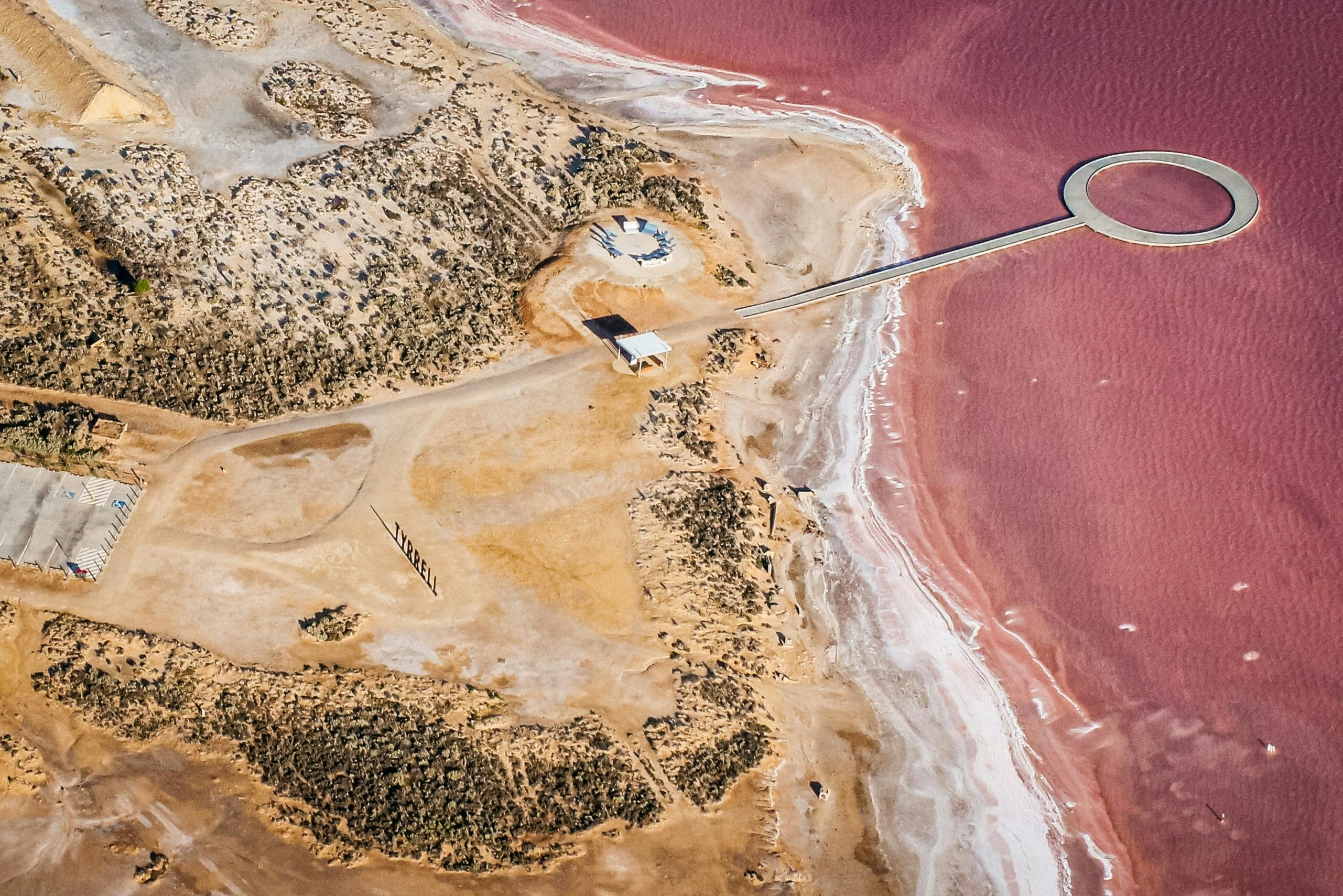 Aerial image of pink Lake Tyrrell showing viewing platform and sand coloured lake edge.