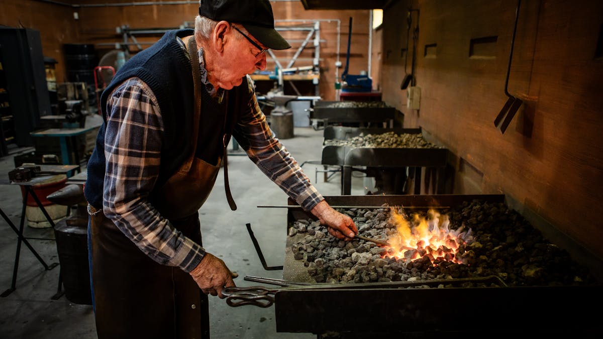 Blacksmith standing at forge with fire lit