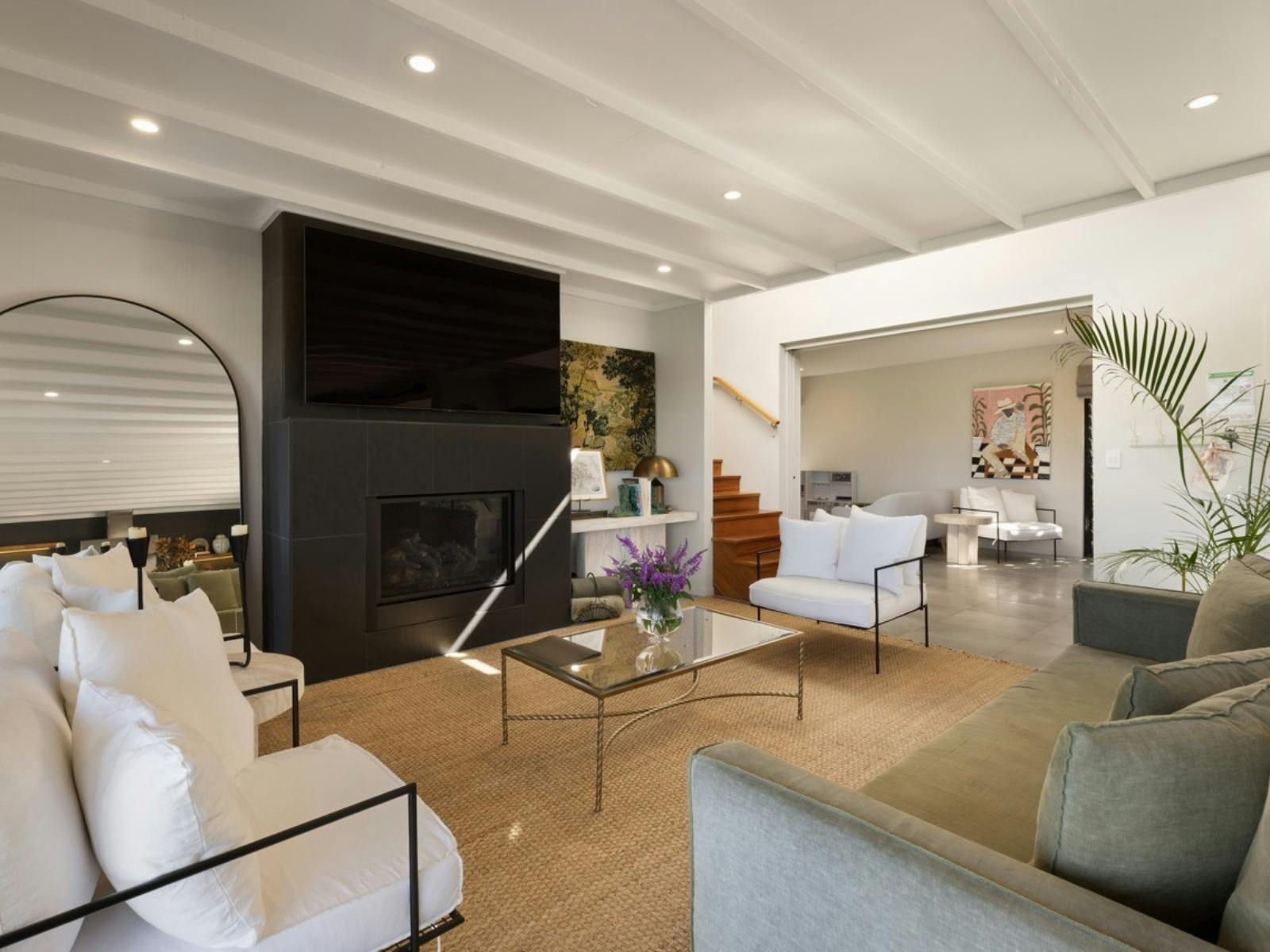 Living area featuring fireplace, artwork, timber staircase and designer furnishings.