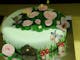 Round cake iced in pale green decorated with flowers, leaves, butterflies and toadstools.
