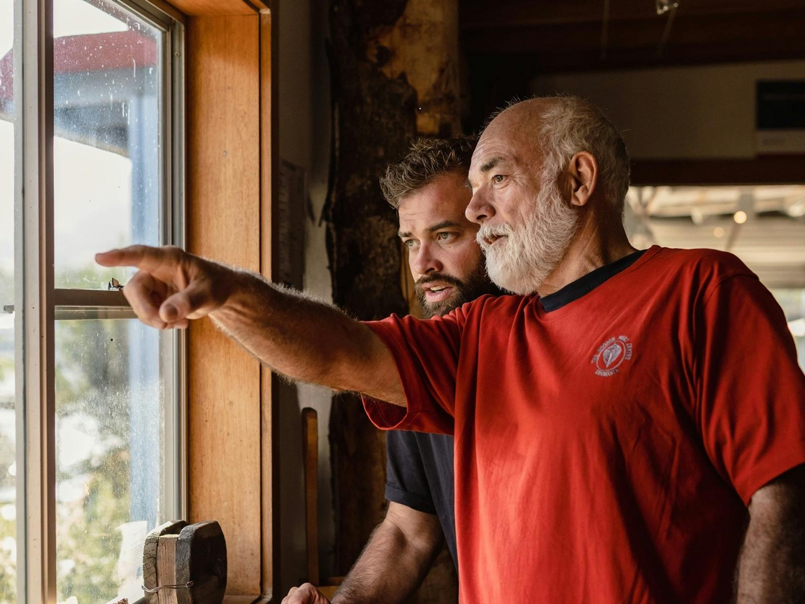volunteer pointing out something through the window to a second person.