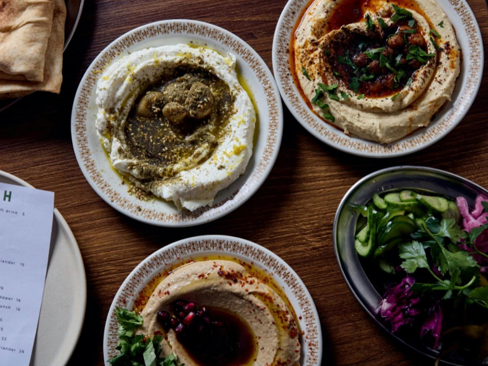 Three Middle Eastern dips topped with herbs and spices, served to share.