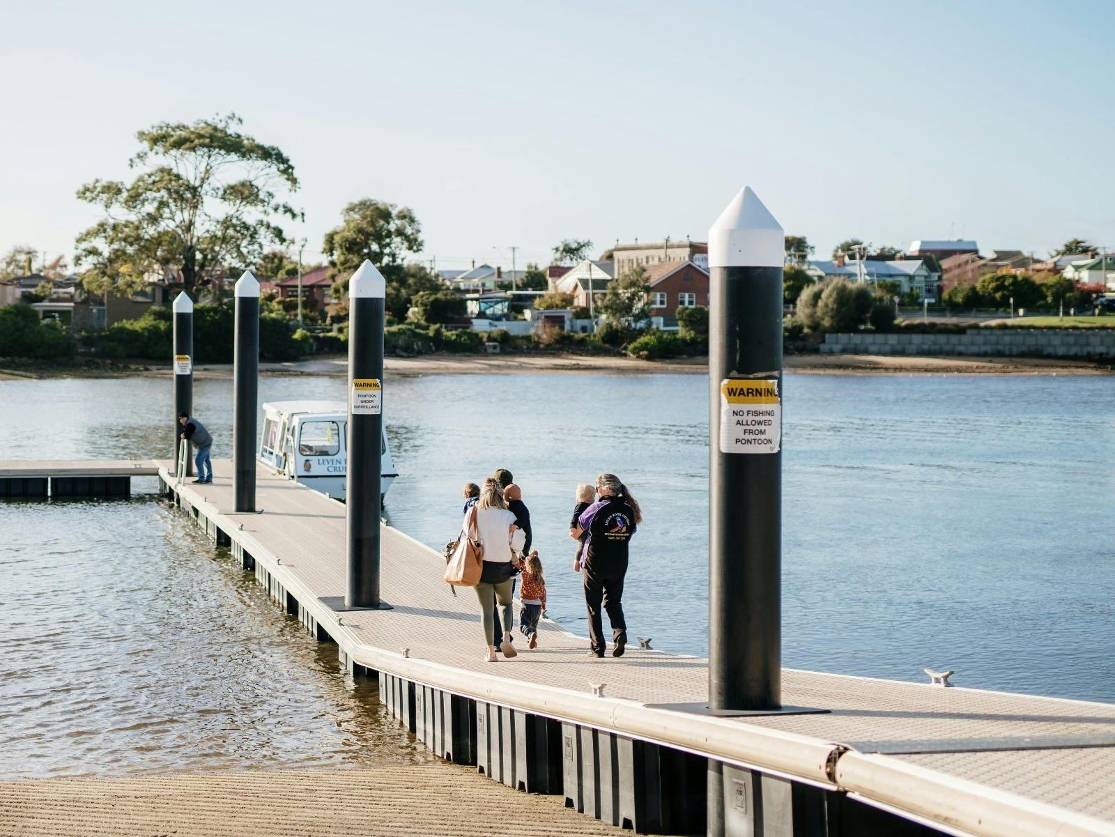 Jus' Leven (boat) at jetty in West Ulverstone, family walking down jetty towards boat.