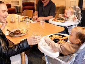 Family seated at table with young children enjoying meals in dining room