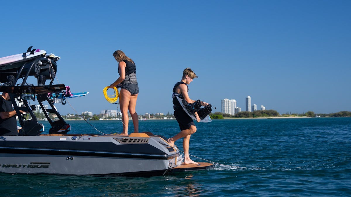 Two riders on the back of the boat preparing to hit the water
