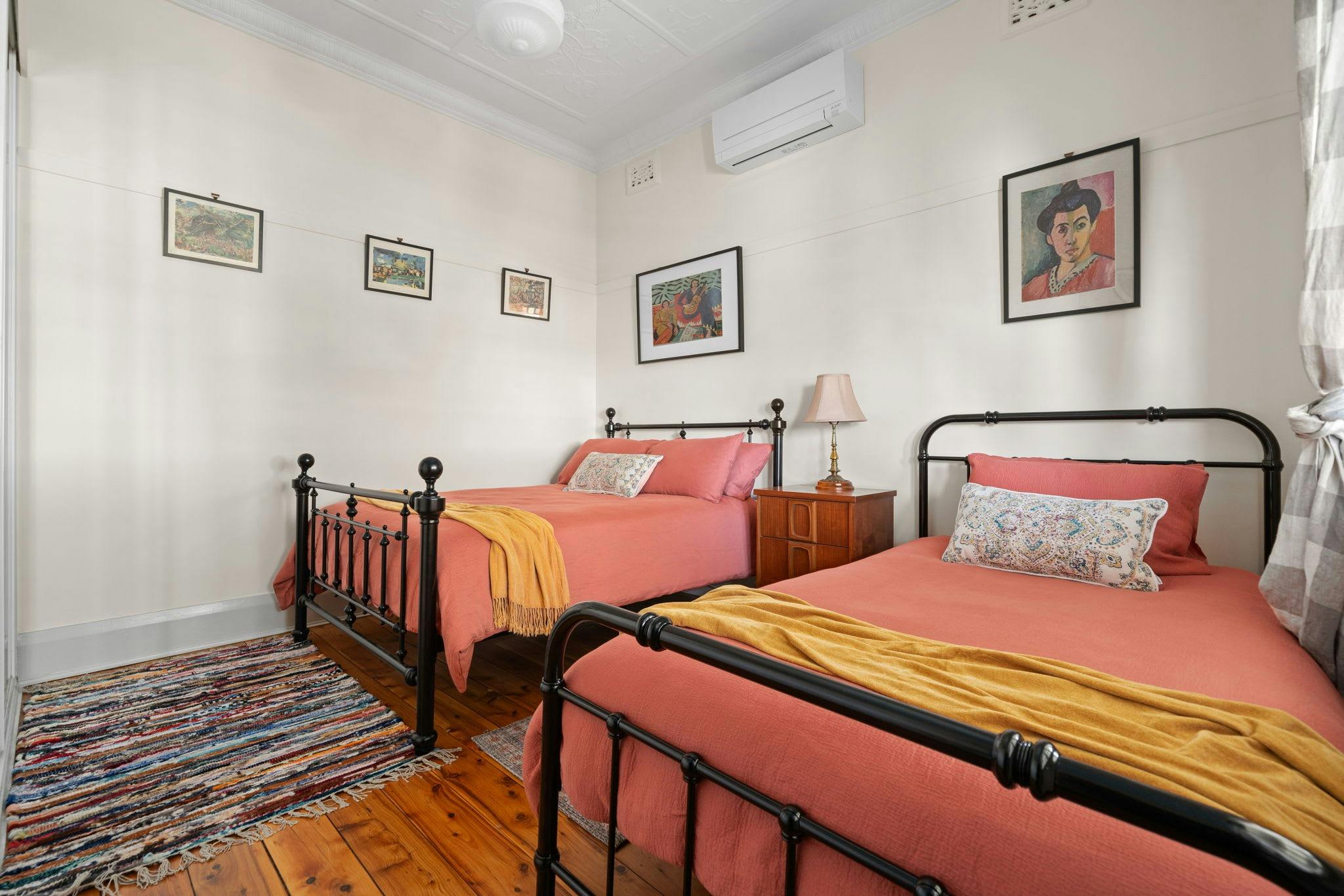 ベッドルーム1室にはダブルベッドとシングルベッドがあります。どちらのベッドにもピンクの掛け布団カバーと黄色のブランケットが付いています。