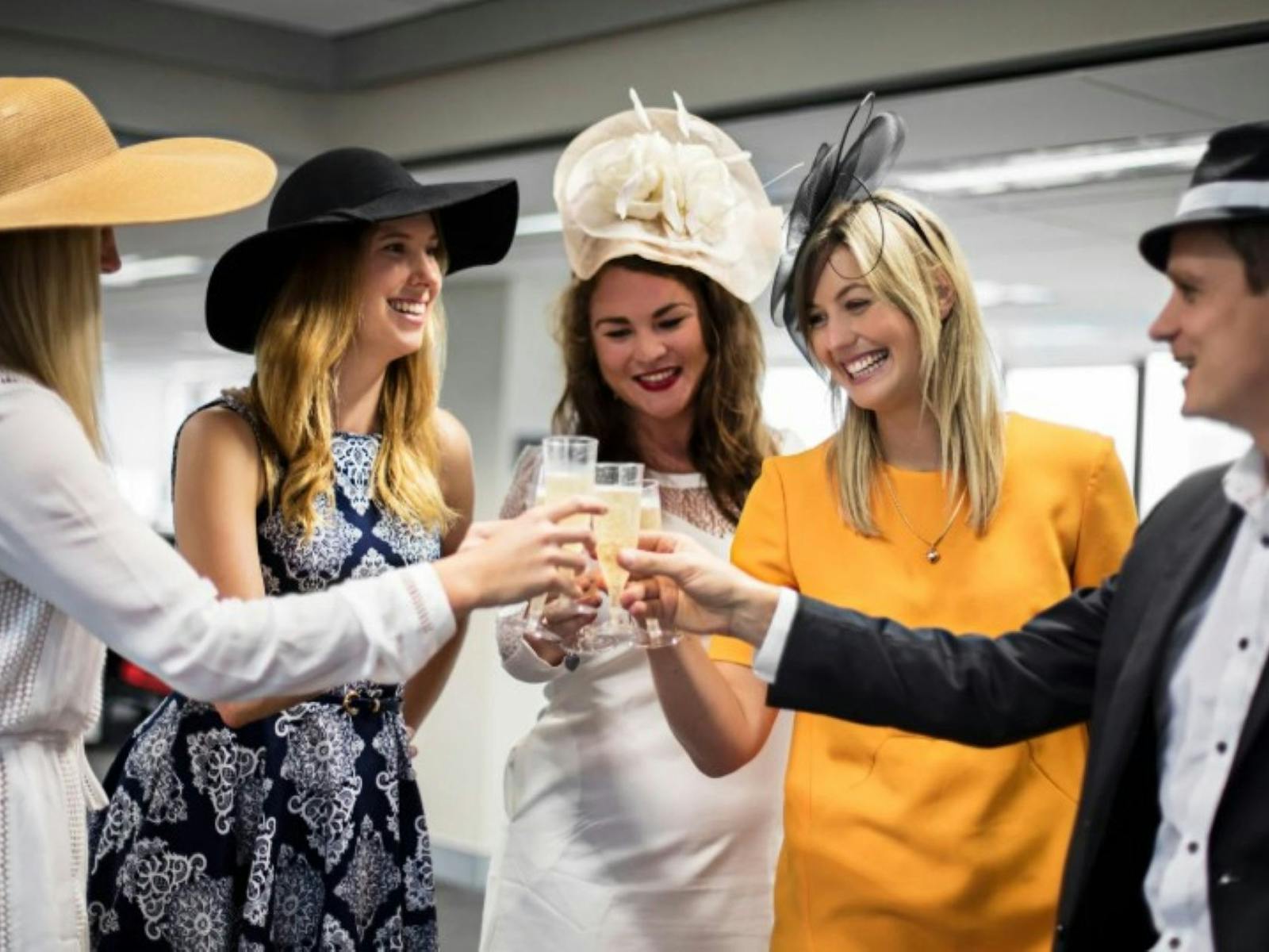 Five fancy dressed people celebrating with glasses of champagne