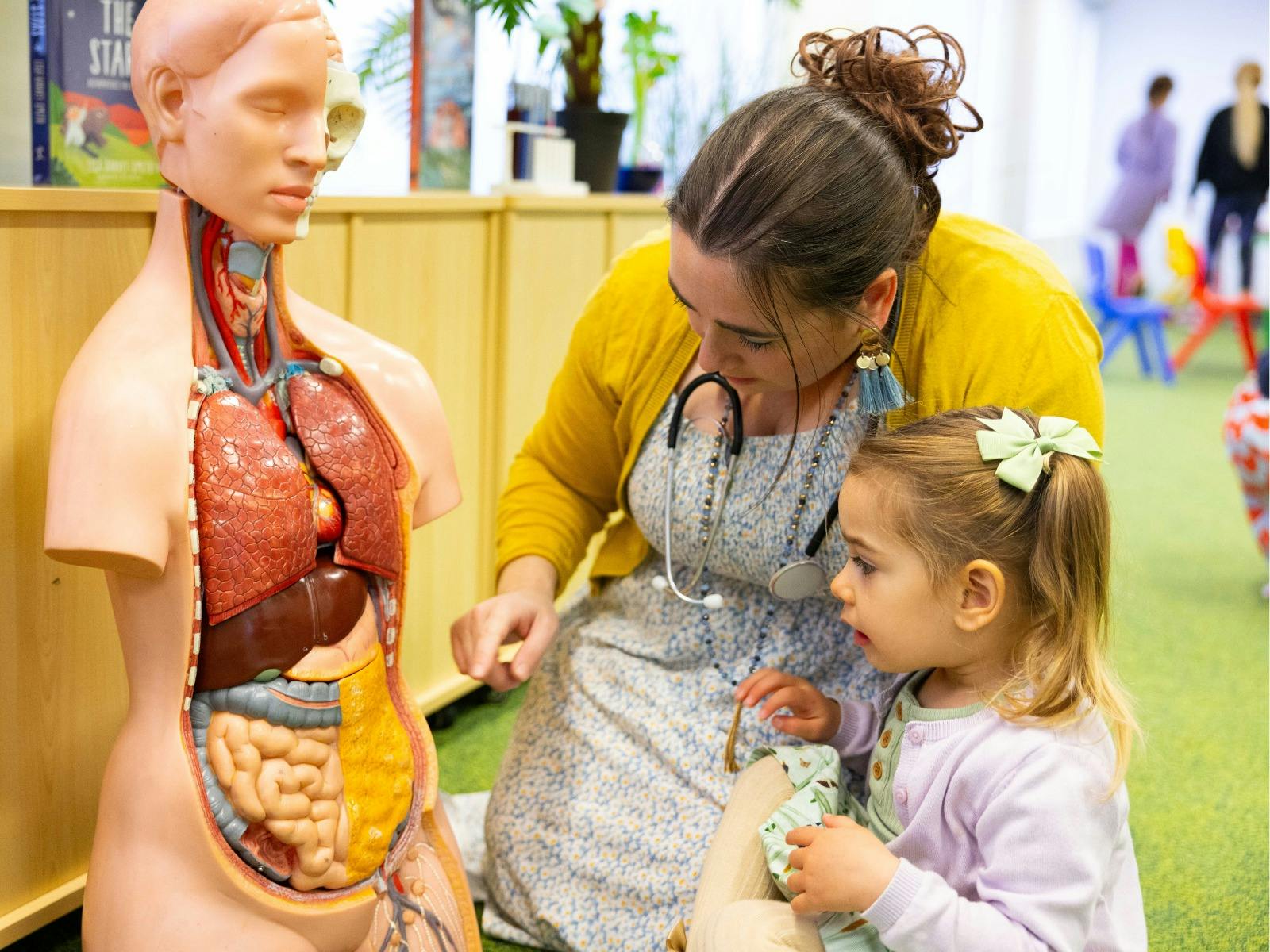 A young girl and woman exploring a human dummy