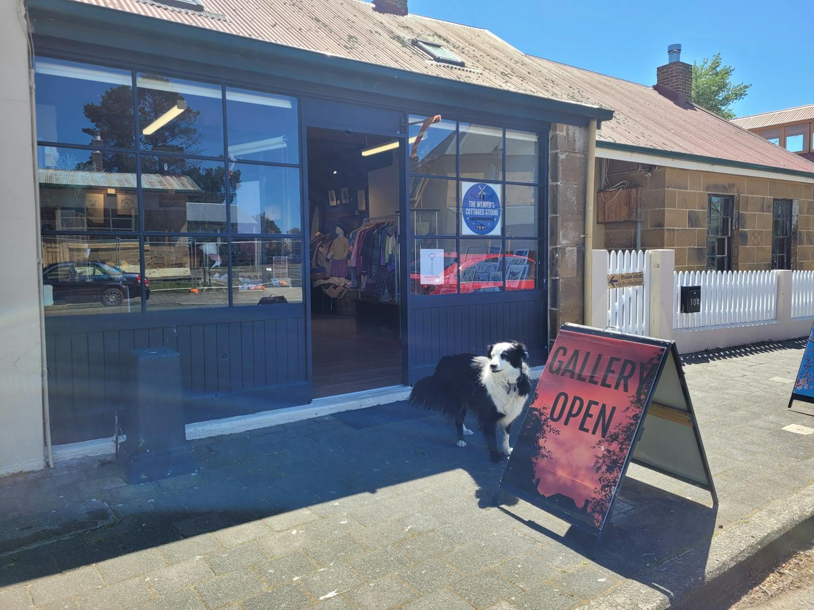 Shop front of Georgian cottage with welcoming Border Collie dog and open signs.