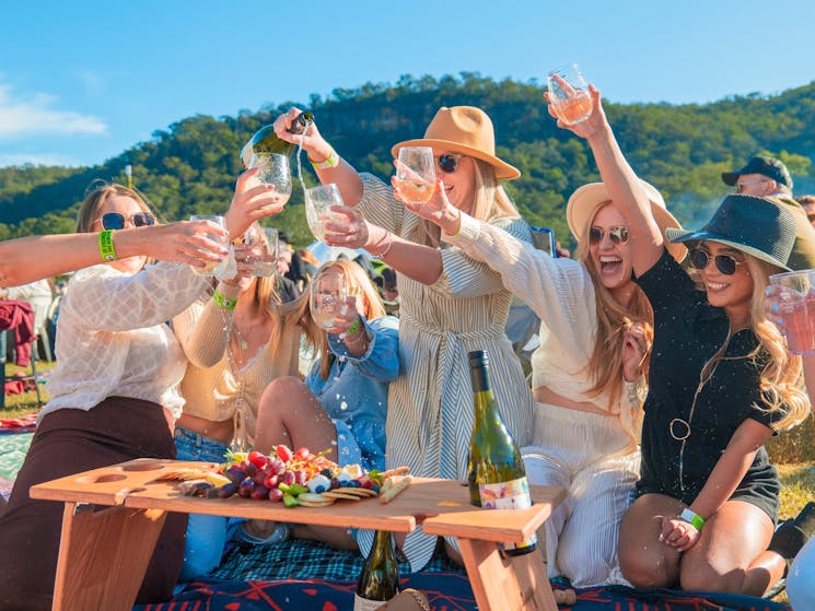 Ladies pour wine into glasses over a grazing board