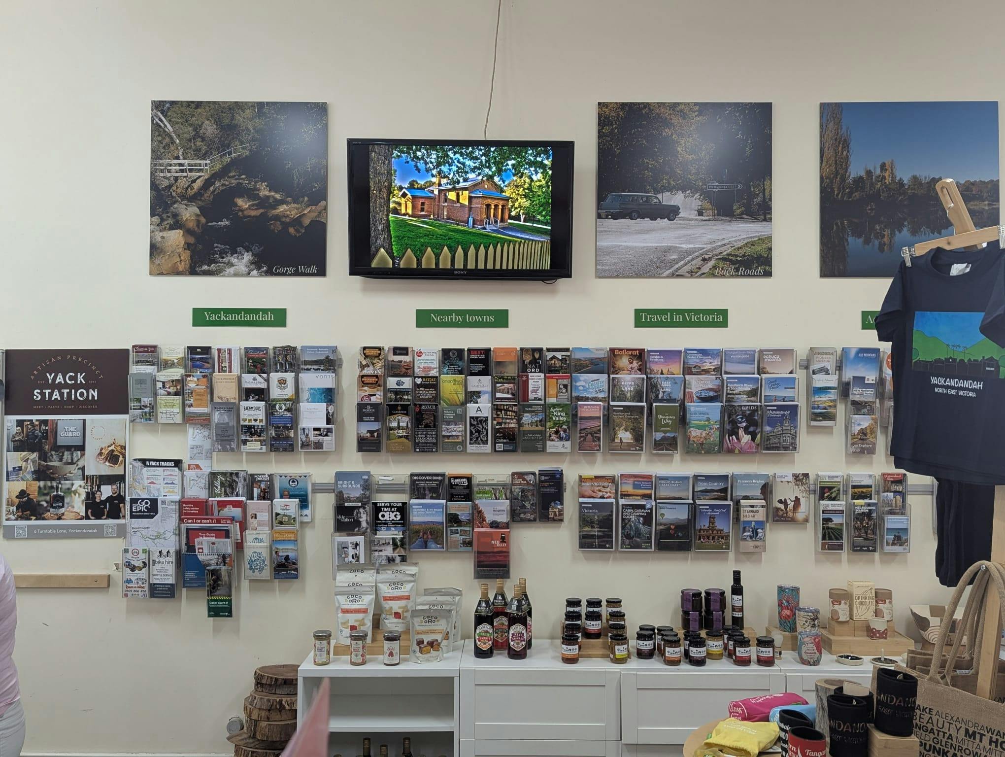 a wall oif broochures sits above a bench with produce and souvenirs inside the building