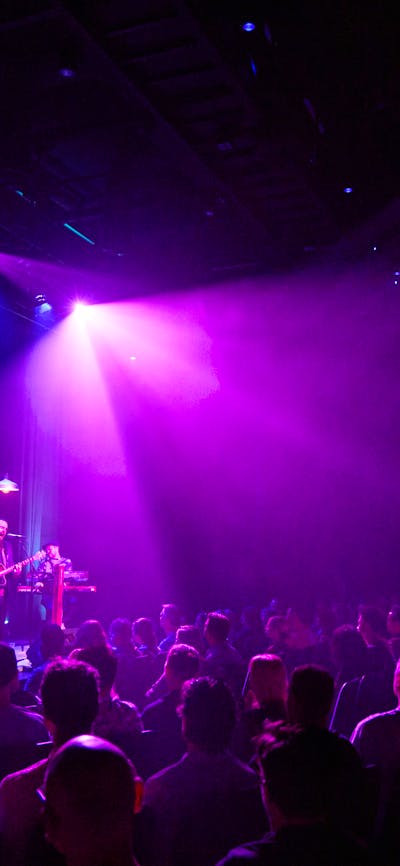 Alex Lloyd and his band play before a full crowd of seated people in the Belco Arts Theatre.