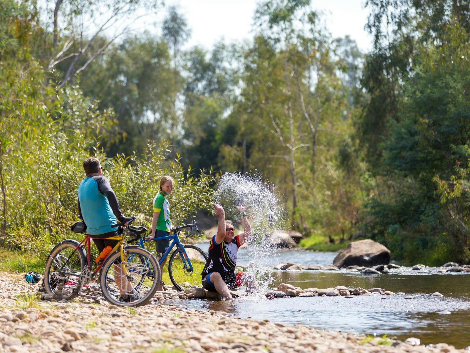 Gravel Road Bikes, Cyclists, trees, riverbank, splashing water in the King River