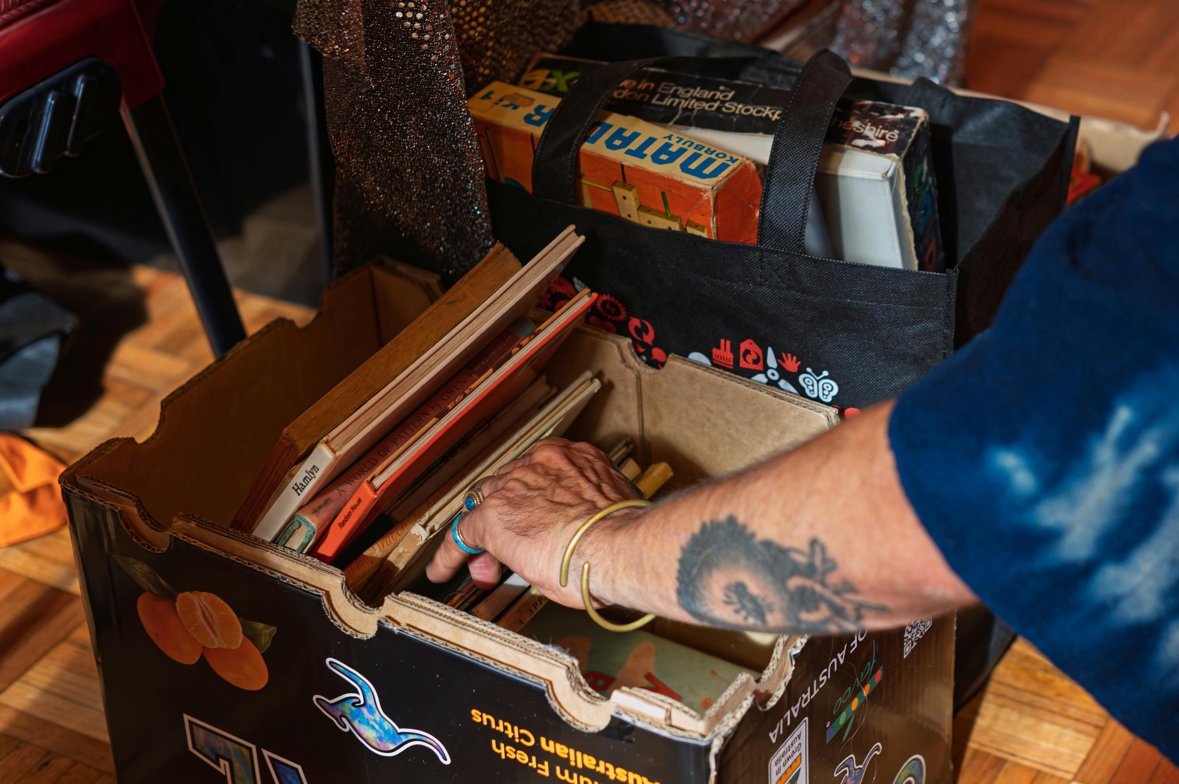 A hand sorting through a cardboard box of vintage books.