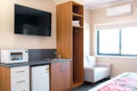 Kitchenette with a large TV and wooden storage space and white couch