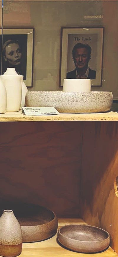 Art and fashion book covers next to ceramic bowls and vessels