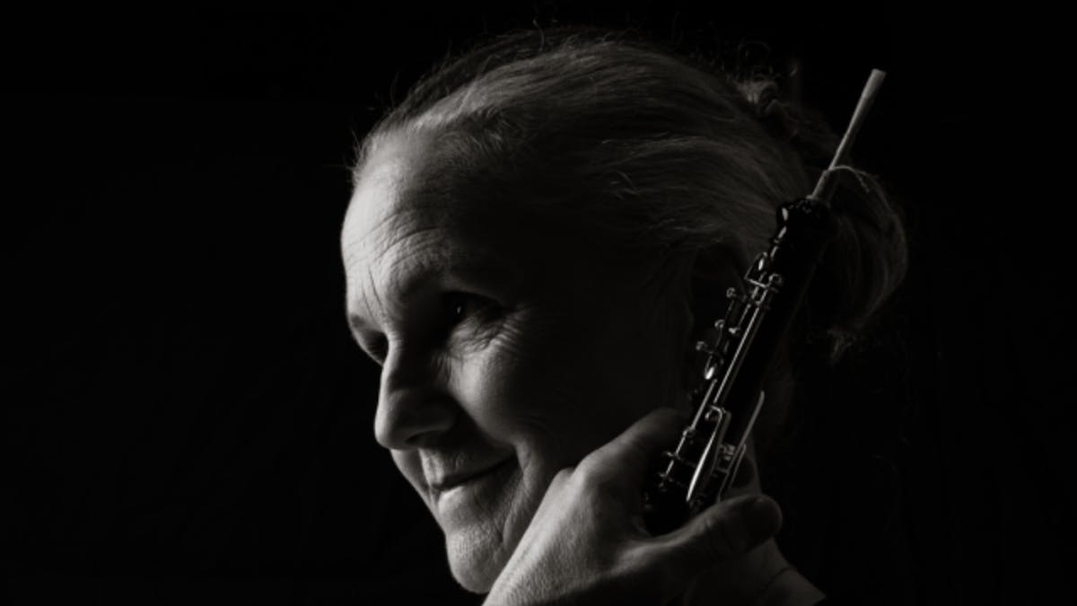 Black-and-white portrait of an oboe player in profile, looking toward the light