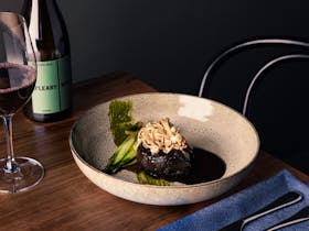 Beef topped with sautéed enoki mushrooms, alongside a glass of Adelaide Hills Shiraz
