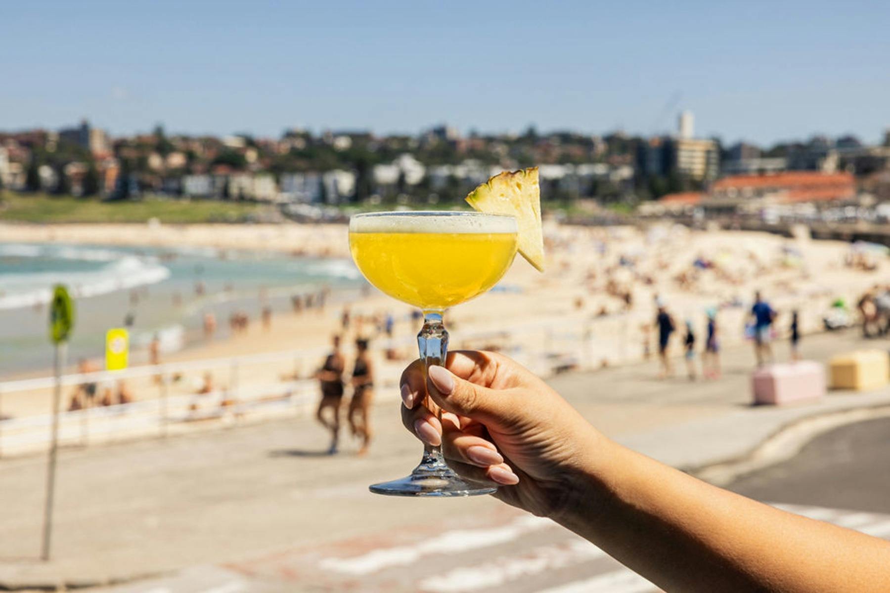 해변 앞에서 칵테일을 들고 있는 손