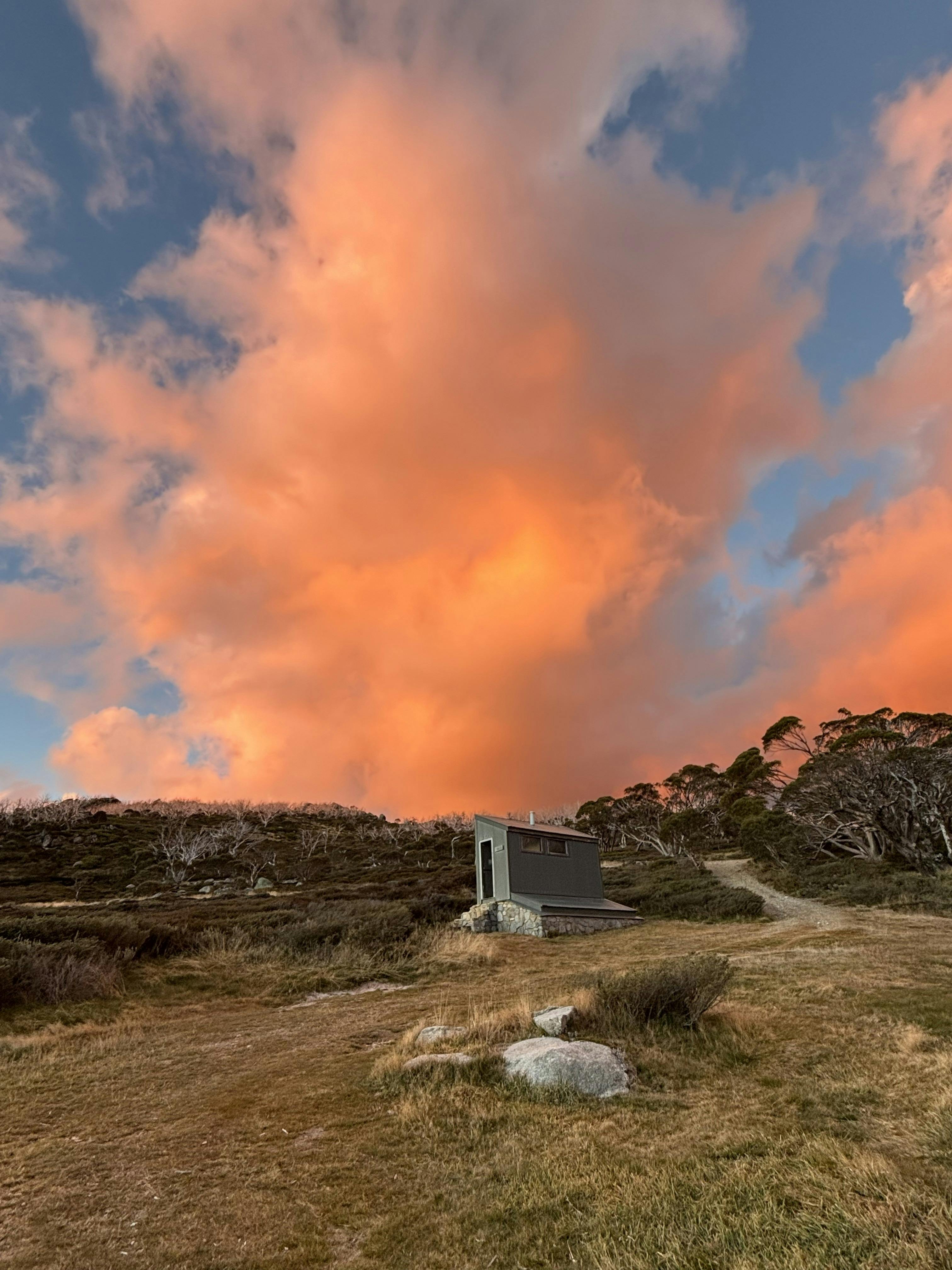 A small tin out door toilet silhouetted against an evening sky