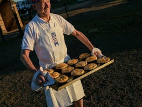 A baker holding a tray of baked goods at the Farina bakery