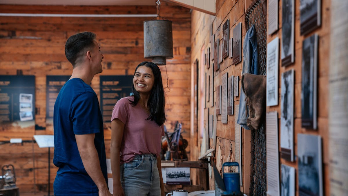 A man in a blue shirt and woman with a pink shirt and dark hair looking at a wall display