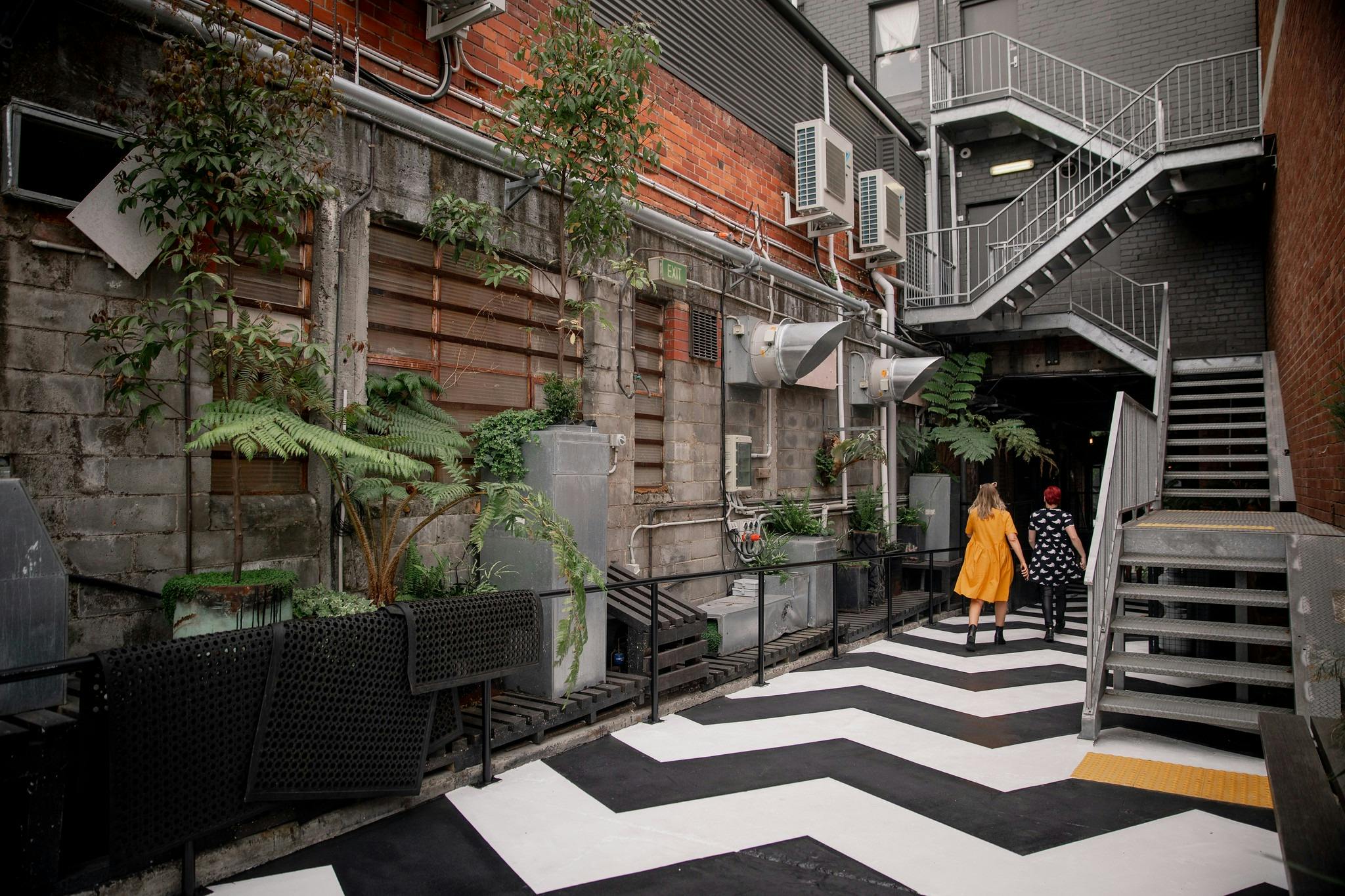 A black and white zig-zag path with two people walking along it against a concrete wall