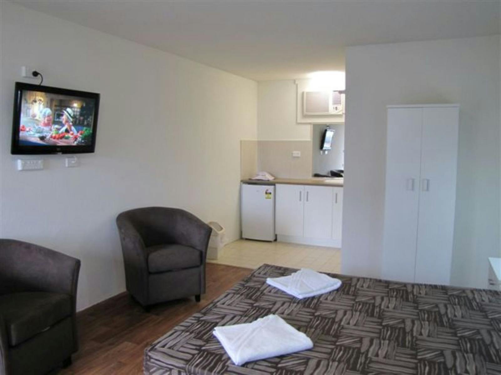 Bedroom with a bed, tv, lounge chairs and kitchenette