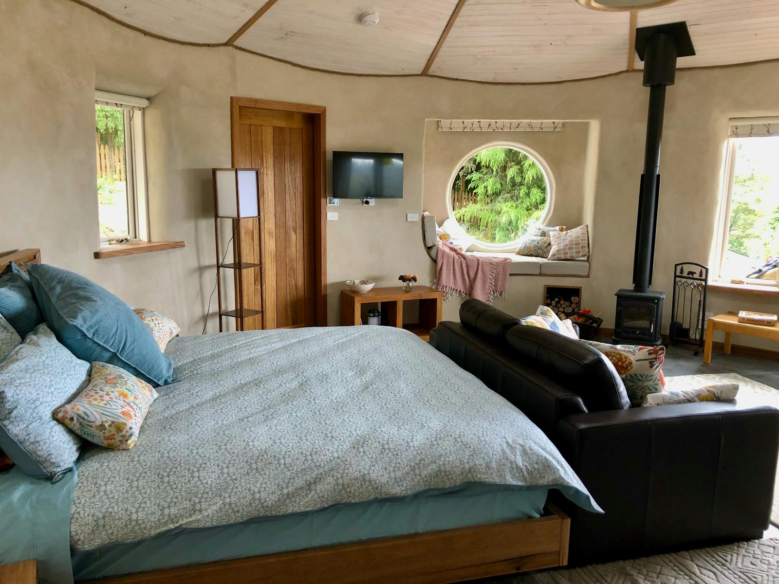 Interior of Otter roundhouse showing bed, sofa, nook, and woodstove