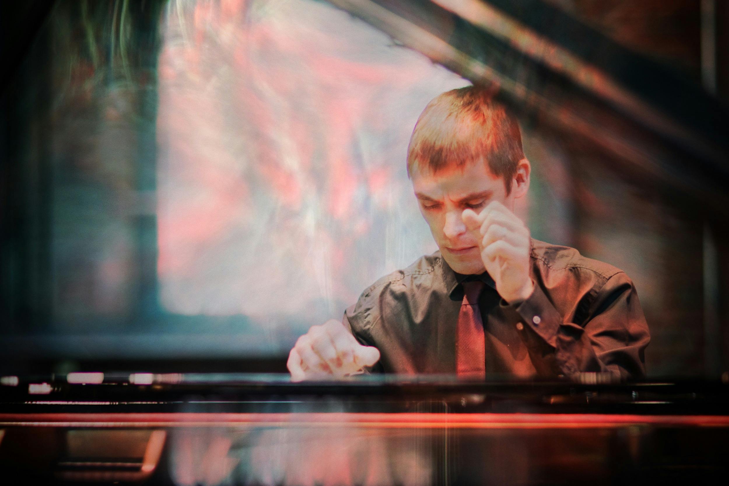 Pianist Cédric Tiberghien playing a piano with a surrealistic overlay of red and blue colours