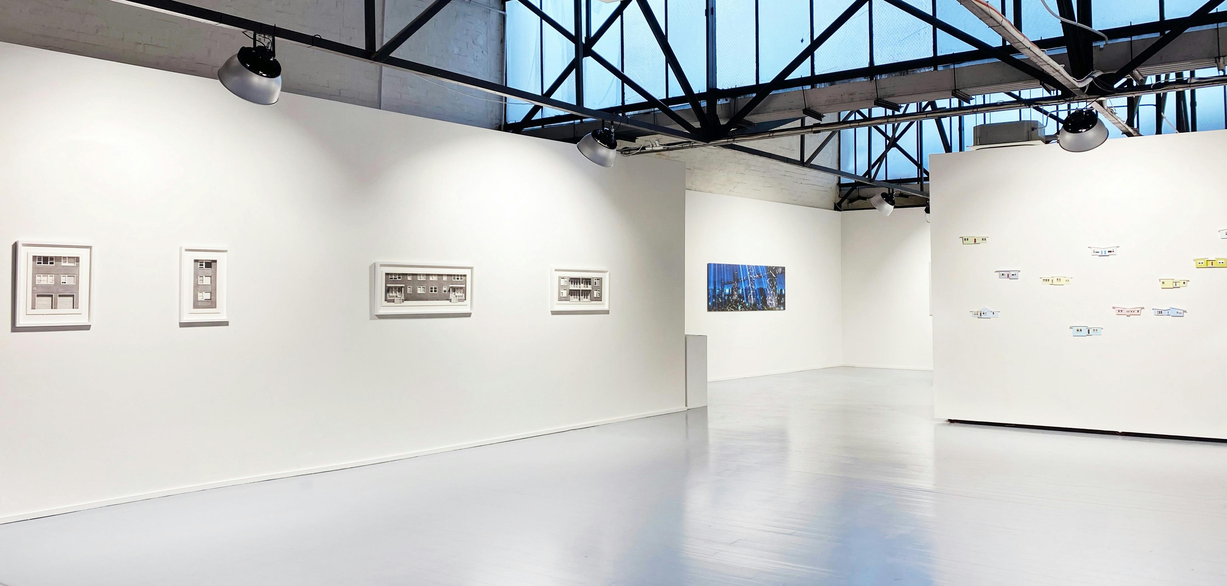 Open gallery space with three artworks mounted on the walls
