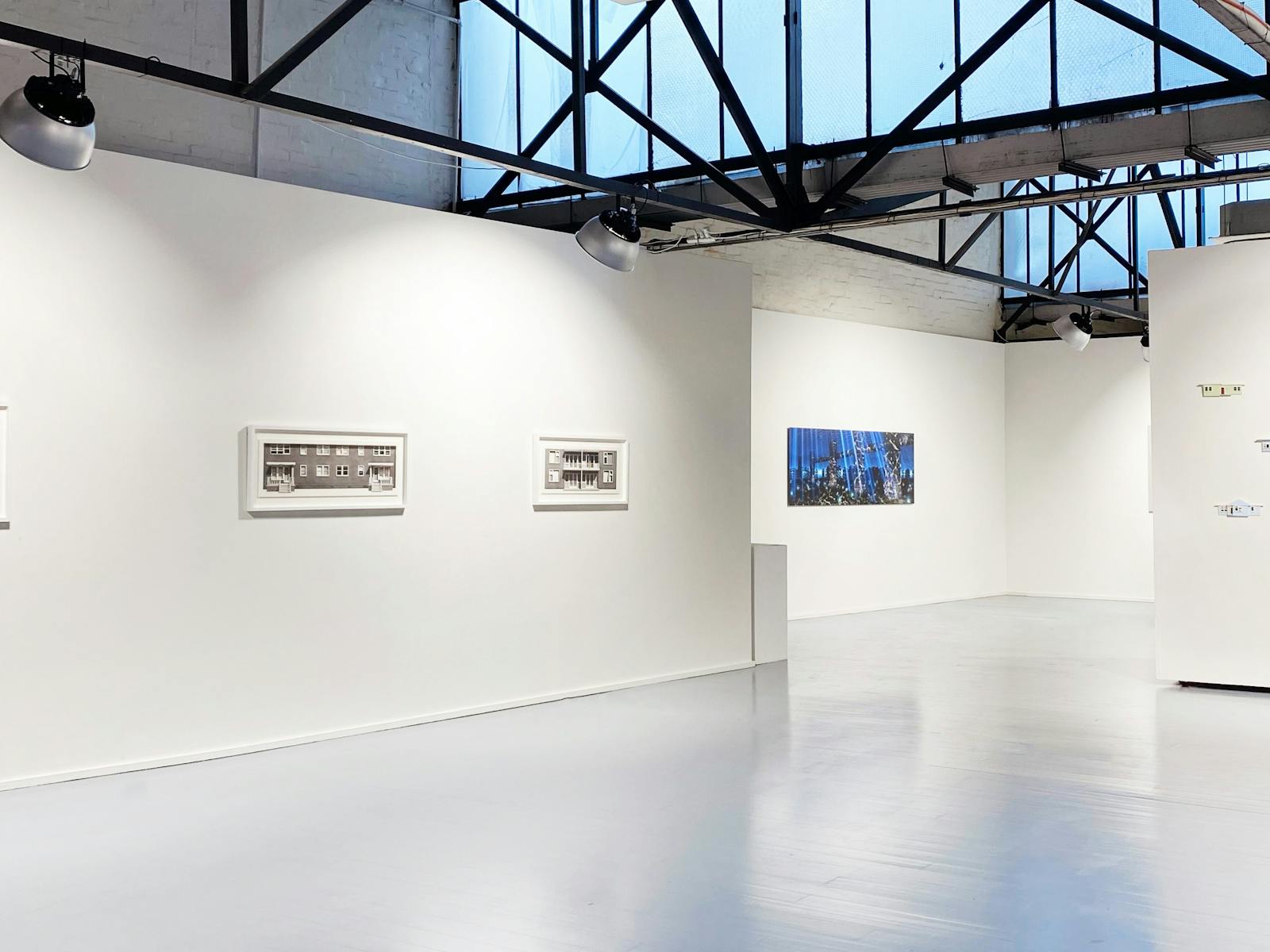 Open gallery space with three artworks mounted on the walls