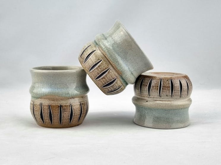 Three cups white background, light blue glaze on top carved decoration bottom stacked in a pyramid