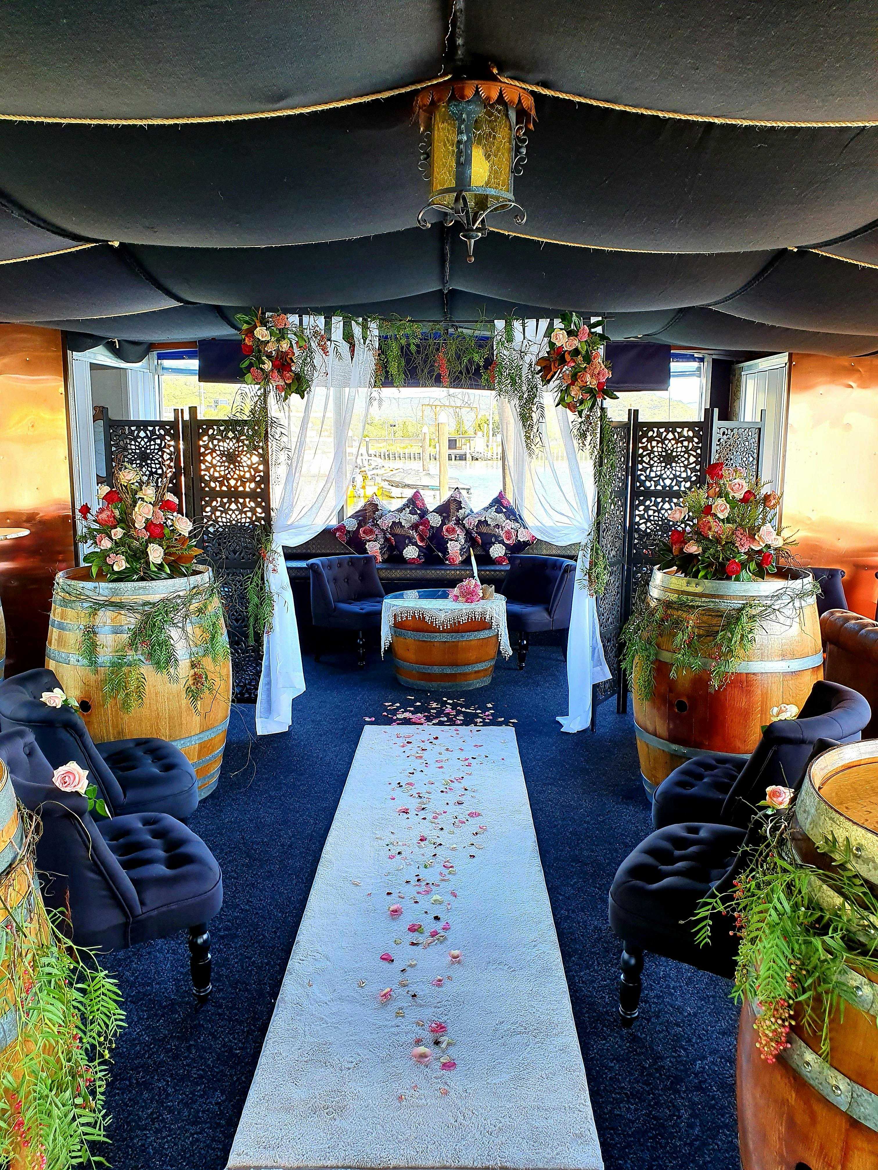 Wedding inside The Floating Oyster Wine Bar. Flowers on the wine barrels, and a white carpet isle.