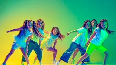 Image of young girls dancing with coloured lighting in background