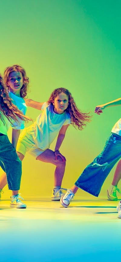 Image of young girls dancing with coloured lighting in background